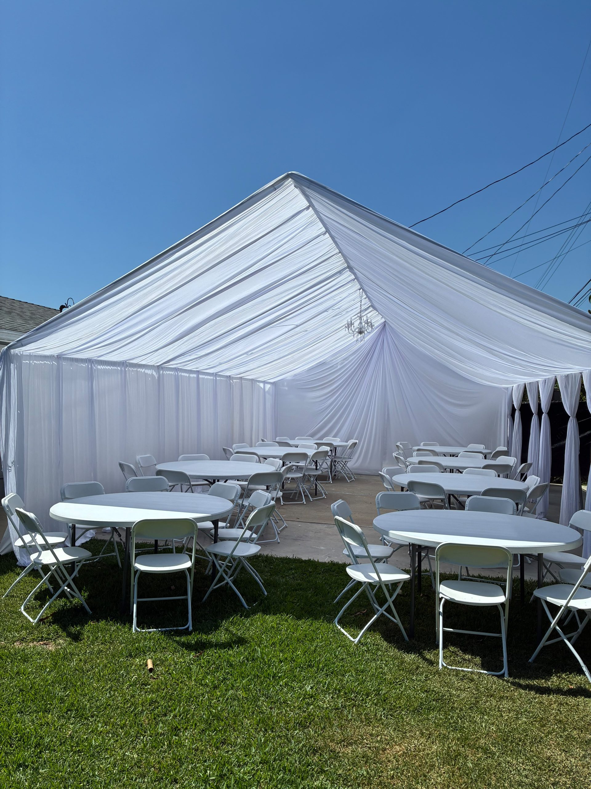 Real Loren's Party Rentals Bright all-white tent draping with tables and chairs. Style inspiration, not a size-specific product photograph.
