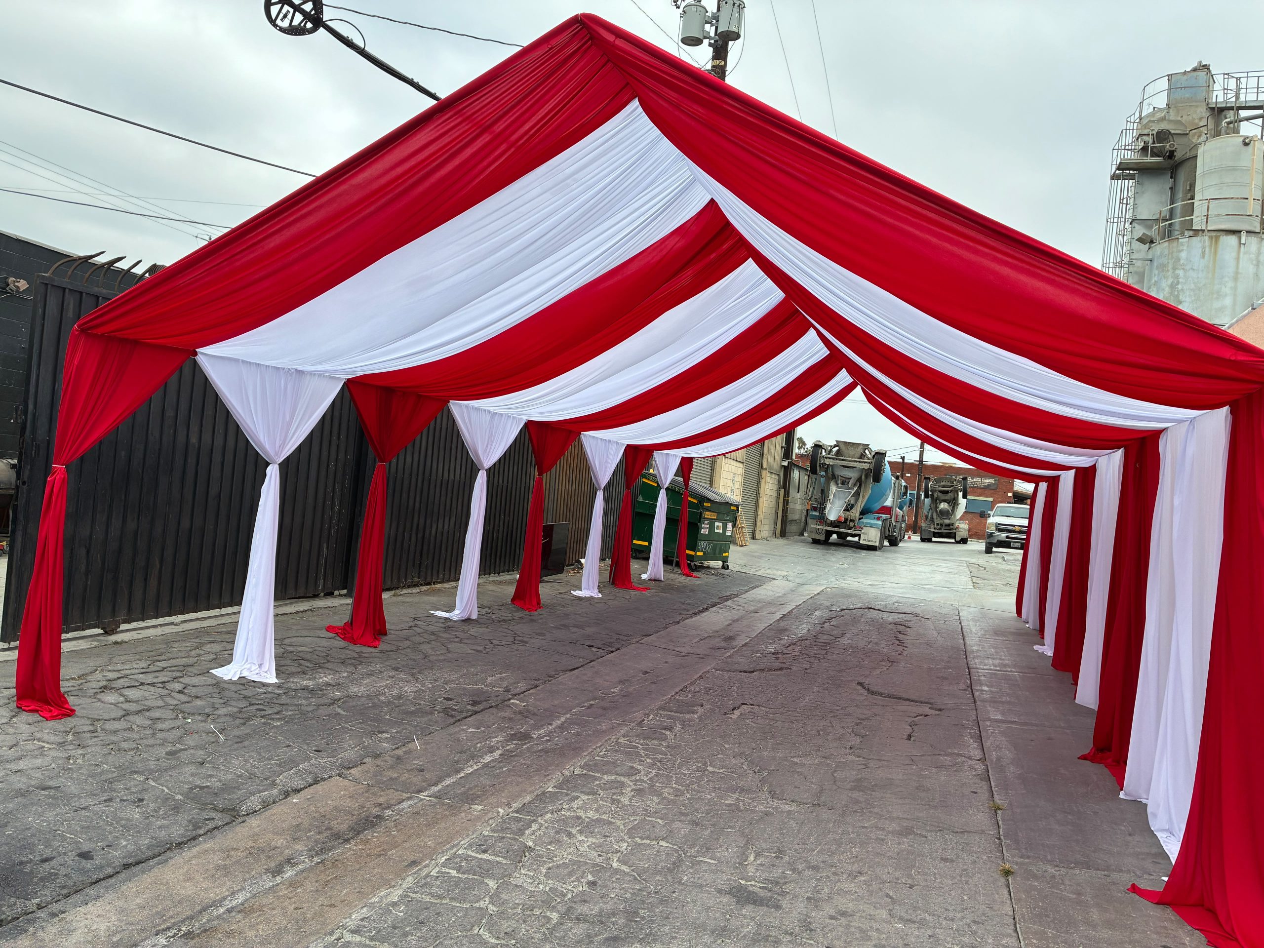 Real Loren's Party Rentals Red and white striped draped tent canopy and side panels. Style inspiration, not a size-specific product photograph.